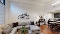 Located at 240 4th St in Inman, SC, this single-floor unit showcases a compelling blend of industrial heritage and contemporary design. The open-concept living area makes an immediate impression with soaring ceilings, a white shiplap ceiling detail, and warm hardwood floors that extend throughout the main living spaces. Oversized black-framed windows flood the rooms with natural light, adding a loft-like industrial character that defines the overall aesthetic.

The kitchen is well-appointed with dark cabinetry, granite countertops, a breakfast bar with seating, black appliances, a stainless steel refrigerator, and recessed lighting. A prominent structural steel column adds an authentic industrial touch to the space. The kitchen flows seamlessly into the dining and living areas, making it ideal for entertaining.

The bedrooms continue the soaring ceiling heights, with large black-framed windows offering generous natural light. Each bedroom features plush carpeting, ceiling fans, and closets with built-in shelving for ample storage. The bathrooms are finished with dark vanity cabinetry, granite countertops, large mirrors, and hardwood-style flooring, with one bathroom offering a shower-tub combination. An additional flexible room with tall ceilings and hardwood floors provides space adaptable to various needs.