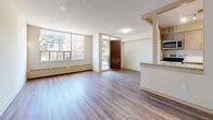 This 2-bedroom, 1-bathroom unit is thoughtfully laid out across a single floor, offering a functional and comfortable living environment. The open-concept living and dining area is generously proportioned, featuring hardwood-style plank flooring, a textured ceiling, and large windows that flood the space with natural light while providing views of the surrounding greenery and neighboring buildings. A balcony door extends the living area outdoors, enhancing the sense of openness.

The kitchen is efficiently designed in a galley layout, equipped with stainless steel appliances including a range, microwave, and refrigerator. Taupe cabinetry, a white tile backsplash, light tile flooring, and a granite-topped breakfast bar add a contemporary touch.

Both bedrooms are well-sized, with the primary bedroom offering a mirrored sliding-door closet and its own window. The second bedroom also features a window and baseboard heating. Hardwood-style flooring carries throughout both rooms, maintaining a cohesive aesthetic.

The bathroom includes a soaker tub framed by full-height marble-style tile surround. A connecting hallway links all rooms efficiently. Baseboard heating is present throughout, ensuring year-round comfort in this clean, move-in ready unit.