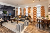 Located at 3999 Highland Crest Way in Knoxville, TN, this single-floor residence delivers a well-organized layout with a lively, sports-inspired aesthetic throughout. The open living area serves as the heart of the home, anchored by a bold football-themed wall mural, arched windows dressed in vibrant orange polka-dot curtains, and Tennessee Volunteers accent pieces that give the space a distinctive, energetic character. Wood-look flooring runs through the main living areas, adding warmth and continuity.

The kitchen is thoughtfully designed with white cabinetry, stainless steel appliances, and a generous marble-topped breakfast bar with barstool seating — ideal for casual dining or entertaining. Track lighting overhead adds a modern touch to the functional workspace.

The bedrooms are comfortably sized, each featuring ceiling fans, ample natural light, and private or adjacent bathroom access. The bathrooms are well-appointed with marble vanity tops, wood-look flooring, and stylish décor accents. A dedicated laundry room with a full-size washer and dryer provides added everyday convenience.

Overall, this residence offers a practical and personality-filled layout that blends comfort with a strong sense of local pride, making it a welcoming home in the Knoxville community.