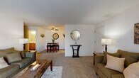 Located at 6840 Schroeder Rd in Madison, WI, this single-floor residence offers a well-organized and functional layout designed for comfortable everyday living. The living room is generously proportioned, featuring wall-to-wall carpeting, neutral tones, and a large sliding glass door dressed with vertical blinds and sheer curtains that invite natural light. The open flow from the living area leads into a defined dining space, complete with a ceiling fan and direct adjacency to the kitchen, making it ideal for both casual meals and entertaining. The kitchen features warm oak cabinetry, light countertops, and wood-style flooring, providing a practical and inviting space for cooking. A dedicated dining area sits just off the kitchen, offering a seamless connection between the two spaces. The bedroom is a comfortable retreat with carpeted flooring, a window with blinds and sheer curtains for natural light control, and ample space for furnishings. The full bathroom includes a wide vanity with a large mirror, oak cabinetry, and a shower-tub combination, finished in neutral tones for a clean, classic look. Throughout the unit, the consistent use of soft carpeting, neutral walls, and warm wood accents creates a cohesive and welcoming ambiance.