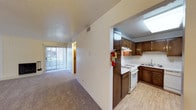 Located at 2215 Ambassador Rd NE in Albuquerque, New Mexico, this single-floor residence offers a practical and comfortable layout designed for everyday living. The open-concept living and dining area is finished with neutral carpet and features a ceiling fan with light fixture, providing airflow and ambiance. A sliding glass door with vertical blinds connects the living space to an outdoor patio, inviting natural light into the interior.

The kitchen is positioned adjacent to the main living area and is well-appointed with rich dark wood cabinetry that extends to the upper and lower walls, offering generous storage. Light wood-look flooring grounds the space, and a skylight overhead brightens the room naturally. White appliances include a gas range with overhead ventilation, a dishwasher, a refrigerator, and a double-basin sink. Ample countertop space supports meal preparation.

The bedroom is a quiet, carpeted retreat with a ceiling fan and a textured ceiling, maintaining consistent design with the rest of the unit. The bathroom includes a full tub and shower combination with a safety grab bar, a clean white surround, and chrome fixtures. Throughout the space, textured ceilings, neutral wall tones, and a cohesive mix of carpet and hard-surface flooring create a straightforward, livable environment.