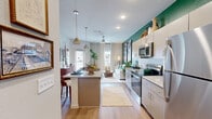 Located at 2902 Pat Booker Rd in Universal City, Texas, this well-appointed one-bedroom, one-bathroom unit offers a thoughtfully designed single-floor layout that maximizes every square foot of its compact footprint. The open-concept kitchen serves as the heart of the home, boasting light gray cabinetry, granite countertops, a subway tile backsplash, and a full suite of stainless steel appliances including a range, microwave, and refrigerator. A peninsula island with an undermount sink and seating provides additional prep and dining space, while bold green accent walls and pendant lighting lend a modern, vibrant character to the space. Warm wood-look luxury vinyl flooring flows seamlessly throughout the living areas. The bedroom is comfortably sized, featuring a ceiling fan, natural light from a large window with views of the outdoors, and direct access to a dedicated walk-in closet outfitted with wire shelving systems for organized storage. The bathroom is finished with a granite-topped vanity, gray cabinetry, a lighted mirror, and wood-look flooring that ties the space together cohesively. A well-maintained green lawn is visible in the exterior view, adding a welcoming outdoor element to this move-in-ready residence.