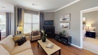 Located at 7781 Gerry Hts in Fountain, Colorado, this single-floor home offers a thoughtfully designed layout with a cohesive, modern aesthetic carried throughout every room. The living room serves as a welcoming centerpiece, featuring warm hardwood-style flooring, crown molding, large windows that invite natural light, and a corner fireplace that adds both warmth and character to the space. Adjacent to the living room, the dining area continues the hardwood flooring and is brightened by multiple windows dressed with elegant draping curtains and blinds, creating an airy atmosphere ideal for entertaining. The kitchen is well-appointed with rich wood cabinetry, granite-look countertops, a decorative tile backsplash, and a full suite of black appliances including a refrigerator, range, microwave, and dishwasher. A dedicated laundry room provides added convenience with full-size washer and dryer units and built-in wire shelving for storage. The bedrooms are carpeted and generously proportioned, offering ample closet space and natural light. The primary bathroom features a dual-sink vanity with granite-look countertops, tile flooring, and a tub-shower combination. A second full bathroom also includes a tub-shower combo and granite-look countertop finishes, maintaining a consistent design standard throughout the home.