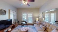 Located at 3200 Bromley Pl in Midland, Texas, this single-story residence offers a well-designed layout with a warm and cohesive aesthetic throughout. The living room serves as an inviting central gathering space, featuring rich hardwood flooring, a ceiling fan with light fixture, and a set of French doors fitted with plantation shutters that allow generous natural light and provide access to the outdoors. The room offers ample space for comfortable seating arrangements. Adjacent to the living area, a dedicated dining room provides an intimate setting for meals, accented by neutral walls and hardwood flooring that continues the home's consistent design language. The kitchen is well-appointed with warm wood cabinetry extending to the ceiling for abundant storage, granite-style countertops, a double stainless steel sink, and black appliances including a range, over-the-range microwave, and refrigerator. Light wood-tone flooring adds brightness to the space. The bedrooms are comfortably sized, featuring plush carpeting, multiple windows with blinds and sheer curtains that invite natural light, and ceiling fans for year-round comfort. The bathroom includes a shower with curtain, vanity with granite-style countertops, and tasteful wall art, completing this functional and well-presented home.