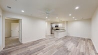 This single-story unit in Ocean Springs, Mississippi, presents a clean, modern aesthetic with a thoughtfully designed open-concept floor plan. The main living area is generously proportioned, featuring light wood-style luxury vinyl plank flooring, recessed lighting, and a ceiling fan that contribute to a bright, airy atmosphere. Windows along the perimeter bring in natural light and offer views of the surrounding greenery.

The kitchen is a standout feature, outfitted with white shaker-style cabinetry, light granite countertops, and a full suite of stainless steel appliances, including a range, microwave, and dishwasher. A peninsula with an undermount sink and pendant lighting above defines the kitchen's boundary with the living space, creating a functional and visually connected layout.

The bedrooms are carpeted for comfort, each equipped with a ceiling fan and windows with blinds. Closet access is available in each room. The bathrooms maintain the unit's clean design language, featuring white vanities with solid-surface countertops, large mirrors, and wood-style or tile flooring. The overall interior palette of white and neutral tones creates a cohesive, move-in-ready environment.