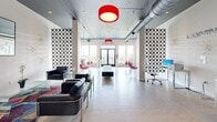 Located at 900 Luxor Ln in Norristown, PA, Sway is a single-floor commercial space that makes an immediate impression with its bold, contemporary design aesthetic. The open-plan layout is defined by crisp white walls, light wood-style flooring, and exposed ductwork running along a dark ceiling — a combination that gives the space an industrial-chic character with a polished edge.

The standout features are the iconic transparent bubble chairs suspended from the ceiling with vibrant red cushions, offering a playful yet sophisticated focal point throughout the space. Striking red drum pendant lights add dramatic pops of color overhead, complementing the monochromatic black-and-white palette of the furniture and decorative laser-cut partition panels.

The main area is generously proportioned and column-accented, creating natural zones for lounging and collaboration. Sleek black leather seating arrangements, tufted benches, and a dedicated workspace with a monitor reflect a versatile, multi-use environment. Geometric wall art, branded signage, and curated greenery in tall planters add texture and personality throughout.

Large windows along the perimeter flood the space with natural light and offer exterior views, enhancing the airy, open ambiance. The overall atmosphere is dynamic, modern, and design-forward — well-suited for creative, social, or professional gatherings.