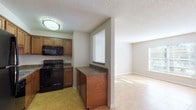 Located at 2770 Roosevelt Blvd in Largo, Florida, this single-floor unit offers a practical and well-organized layout designed for comfortable everyday living. The kitchen is efficiently arranged with warm-toned wood cabinetry, dark granite-style countertops, and a full suite of black appliances including a refrigerator, range, and built-in microwave. Tile flooring runs throughout the kitchen, and a pass-through window connects the space directly to the living area, enhancing openness and flow between rooms. The living area features large tile flooring that reflects natural light streaming in through the windows, creating a bright and welcoming atmosphere. A pass-through opening to the kitchen and a nearby entry door make this a highly connected and accessible common area. The bedrooms are carpeted and offer a cozy feel, each equipped with windows fitted with blinds that allow for natural light and outdoor views of the surrounding greenery. The bathroom includes a full-size tub and shower combination with white tile surround, a toilet, and towel bar. Throughout the unit, textured ceilings, neutral wall tones, and consistent trim work contribute to a clean and cohesive interior aesthetic. The single-floor layout ensures easy accessibility and straightforward navigation throughout the space.
