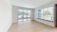 Located at 3558 Elm St in Atlanta, GA, this well-appointed 2-bedroom, 3-bathroom residence offers a thoughtfully designed single-floor layout. The open-concept living and kitchen area is anchored by light hardwood flooring and large windows fitted with blinds that flood the space with natural light and offer outdoor views. The modern kitchen is a standout feature, boasting a generous white quartz island, two-tone cabinetry combining warm wood tones with crisp white uppers, a subway tile backsplash, stainless steel appliances, and striking amber pendant lighting. The living area extends naturally from the kitchen, with expansive windows providing a bright, airy atmosphere. Both bedrooms are carpeted and feature ceiling fans, large windows, and ample proportions. The spacious primary bedroom includes direct access to an en-suite bathroom and a walk-in closet area. The bathrooms are elegantly finished with large-format marble-effect tile featuring gold veining — one bathroom offers a soaking tub with tiled surround, while another features a frameless glass walk-in shower. Additional cabinetry with white countertops and hardwood floors add functional detail throughout the home.