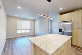 Located in Parker, Colorado, this well-appointed 2-bedroom, 2-bathroom residence showcases a clean, contemporary design with cohesive finishes throughout. The open-concept kitchen and living area serves as the heart of the home, centered around a striking kitchen island topped with a veined quartz countertop. Light wood-tone cabinetry pairs with stainless steel appliances — including a side-by-side refrigerator, built-in microwave, and range — while a textured herringbone tile backsplash adds a refined detail. Sleek pendant lighting illuminates the island, and recessed lighting brightens the entire living space. Wood-look plank flooring flows seamlessly through every room, lending warmth and visual continuity. Natural light enters through multiple windows fitted with roller shades. The primary bedroom connects directly to an en-suite bathroom featuring a glass-enclosed walk-in shower with herringbone tile and a window for natural light. The second bathroom offers a full soaking tub and shower combo with matching tile work and a wood-toned vanity. Both bedrooms are well-proportioned, with dedicated closets providing ample storage. The unit also includes a private exterior entry door, adding convenience and a sense of independence to this modern Parker residence.