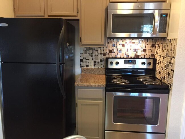 Kitchen w/ stainless steel stove and microwave. - 8633 Datapoint Drive #268