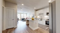 Located in New Braunfels, TX, this well-appointed one-bedroom, two-bathroom residence offers a thoughtfully designed open-concept floor plan. Wood-look flooring flows throughout, tying together each space with a clean, contemporary aesthetic.

The kitchen serves as the centerpiece of the main living area, featuring crisp white shaker cabinetry, a geometric hexagonal tile backsplash, granite countertops, stainless steel appliances, and a central island with bar seating — ideal for both everyday cooking and casual entertaining.

The living room is bright and inviting, benefiting from an array of large windows and a glass door that opens to an exterior balcony, flooding the space with natural light and offering outdoor views. A ceiling fan adds both comfort and style.

The bedroom is a comfortable, well-proportioned retreat with natural light from dual windows and its own ceiling fan. It is complemented by a dedicated walk-in closet with multi-tiered shelving and hanging rods, providing generous storage.

The two bathrooms include a full bath with a soaking tub surrounded by large-format neutral tile and brushed nickel fixtures, lending a clean, spa-like feel. The overall palette of warm neutrals and white finishes creates a cohesive, modern ambiance throughout the residence.