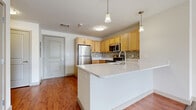 Located at 1373 Mt Hope Ave in Rochester, NY, this three-bedroom, two-bathroom single-floor residence offers a well-organized layout across a comfortable footprint. The entryway greets residents with warm hardwood-style flooring and a secure paneled entry door, setting a clean, modern tone throughout.

The kitchen is a standout feature, equipped with stainless steel appliances including a refrigerator, range, and microwave. Light maple cabinetry pairs with a tile mosaic backsplash and a generous island with a white countertop surface, ideal for both cooking and casual dining. Pendant lighting above the island adds a refined touch, while the hardwood-style flooring extends seamlessly through the kitchen and into the combined dining and living area.

The three bedrooms are carpeted for comfort, each offering a bright, neutral palette. The primary bedroom includes its own walk-in closet with wire shelving and dedicated storage space. In total, five closets are distributed throughout the unit, providing ample storage. The two bathrooms feature hardwood-style flooring, warm-toned cabinetry, and a full tub-shower combination. An in-unit laundry area adds everyday convenience. The overall design is clean and functional, making this a practical and comfortable Rochester residence.