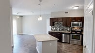 This single-story residence in Leander, TX offers a thoughtfully designed layout across two bedrooms and two bathrooms. The open-concept kitchen and living area serves as the heart of the home, anchored by a granite-topped center island illuminated by stylish pendant lights. The kitchen features rich dark-toned cabinetry, a mosaic tile backsplash, stainless steel appliances including a refrigerator, range, microwave, and dishwasher, and ample counter space. Wood-look plank flooring extends throughout the main living and kitchen areas, adding warmth and continuity.

The spacious primary bedroom includes plush carpeting, multiple windows for natural light, a ceiling fan, and direct access to an en-suite bathroom with dark cabinetry. The second bedroom also features carpet flooring, a ceiling fan, and natural light from multiple windows. Additional areas finished with wood-look plank flooring provide flexible utility space. The second bathroom includes a soaking tub with white tile surround and chrome fixtures. Neutral wall tones throughout create a clean, cohesive aesthetic well-suited to a variety of décor styles.