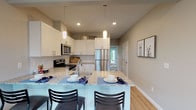 This single-floor residential unit offers a well-organized and functional layout designed for comfortable everyday living. The entryway greets residents with tile flooring and a baseboard heating unit, setting a practical tone for the rest of the home.

The open-concept kitchen flows seamlessly into the living area, making it ideal for both daily routines and casual entertaining. The kitchen is outfitted with warm oak cabinetry offering generous storage, light-toned countertops, a stainless steel sink, a dishwasher, and an electric range. Tile flooring carries through the kitchen and dining transition zone, giving way to soft neutral carpeting in the living space. The living room benefits from natural light through dual windows and a sliding glass door that opens to a private patio, covered by vertical blinds.

Two carpeted bedrooms provide quiet retreats, each dressed in the same warm cream palette found throughout. One bedroom features a large built-in closet with wooden sliding doors. Both bedrooms are served by their own dedicated bathrooms — one with a full soaking tub and mirrored medicine cabinet, and the other with a standalone shower stall — both finished with tile flooring and warm wood vanities. A textured ceiling detail is found in one of the bedrooms, adding subtle character to the space overall.