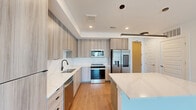 This contemporary 1020 square foot apartment, located at 10 Tower Rd NW in Atlanta, offers a harmonious blend of style and functionality. The open-concept floor plan maximizes the use of space, creating a seamless flow between the living areas. The living room is bathed in natural light, courtesy of floor-to-ceiling windows that frame stunning city views. A modern ceiling fan adds both style and comfort.

The gourmet kitchen is a highlight, featuring sleek wooden cabinetry, stainless steel appliances, and a unique island with built-in wine storage. The island, with its light blue accent, serves as both a prep area and casual dining space. Recessed lighting and a statement pendant light fixture enhance the kitchen's ambiance.

The apartment boasts two bedrooms, including a spacious 140 square foot primary bedroom, and two well-appointed bathrooms. One bathroom showcases a floating vanity in a warm wood tone, complemented by large illuminated mirrors. Ample closet space, including walk-in closets with custom shelving, provides excellent storage solutions.

Throughout the apartment, warm wood-toned flooring creates a cohesive look, while crisp white walls offer a blank canvas for personalization. The combination of modern fixtures, clean lines, and thoughtful design elements results in a sophisticated urban living space.