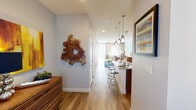This well-designed two-story residence offers a thoughtful layout that balances modern aesthetics with everyday functionality. The entry hallway sets a welcoming tone, accented by artistic wall décor and warm wood-style flooring that carries throughout the home. The kitchen is a standout feature, showcasing sleek flat-front cabinetry in a rich wood finish, granite countertops, stainless steel appliances including a gas range and built-in microwave, and a peninsula with bar seating illuminated by elegant pendant lighting — ideal for both cooking and casual dining. The open living area is bright and inviting, featuring a ceiling fan, sliding glass doors that open to an outdoor balcony, and generous natural light from multiple windows. Upstairs, the bedrooms are comfortable and well-proportioned, each equipped with ceiling fans and large windows that bring in natural light. The primary bedroom is complemented by a spacious walk-in closet with built-in shelving and hanging rods, offering ample storage. The primary bathroom features dual vessel sinks set in granite countertops, providing a clean, modern finish. Throughout the home, neutral tones, recessed lighting, and consistent flooring create a cohesive and polished living environment.