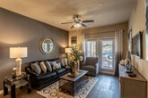 This single-floor residence offers a thoughtfully designed layout that balances comfort and functionality. The living room serves as the heart of the home, featuring rich hardwood-style flooring, a ceiling fan, and French doors that invite natural light and provide access to an outdoor area. A bold accent wall adds depth to the space, complemented by stylish décor and ample room for relaxed entertaining.

The kitchen is a standout feature, showcasing dark espresso cabinetry, granite countertops, a mosaic tile backsplash, and a full suite of black appliances including a refrigerator, range, and dishwasher. A central island with a sink and generous counter space connects seamlessly to a dedicated dining area, making it ideal for both cooking and gathering.

The primary bedroom is generously sized, carpeted for comfort, and includes a ceiling fan and natural light from well-placed windows. It connects directly to a private en-suite bathroom featuring a wide granite vanity, dark cabinetry, dual medicine cabinets, and a clean, modern aesthetic. A second bedroom mirrors this comfortable design with its own ceiling fan and natural light. A second full bathroom, equally well-appointed with matching finishes, completes the layout. Throughout, warm neutral tones and consistent design elements create a cohesive and inviting atmosphere.