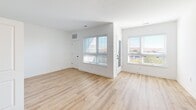 Located at 11 Washington Ave in Carteret, NJ, this thoughtfully designed unit offers a clean, modern aesthetic with an efficient, well-organized layout across a single floor. Light oak hardwood-style flooring flows seamlessly throughout, complementing the crisp white walls and creating a bright, cohesive atmosphere.

The open-concept kitchen and living area serves as the heart of the space. The kitchen is outfitted with stainless steel appliances — including a gas range, built-in microwave, dishwasher, and refrigerator — paired with two-tone cabinetry featuring white upper cabinets and light gray lower cabinets. A striking marble-veined quartz countertop, subway tile backsplash, and a matte black faucet complete the polished look.

The living area is generously lit by multiple windows dressed with horizontal blinds, offering views of the surrounding neighborhood and allowing natural light to fill the room. A private balcony extends the living space outdoors. In-unit laundry is conveniently housed behind paneled doors, adding to the functionality of the layout. Two closets provide ample storage throughout.

The bathroom features a white vanity with quartz countertop, an undermount sink, matte black fixtures, a large mirror, and modern wall-mounted lighting. A utility room rounds out the practical offerings of this well-appointed unit.