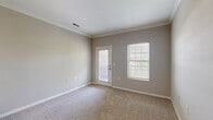 Located at 5300 Patron Pl in North Charleston, SC, this single-floor, 2-bedroom, 2-bathroom home offers a practical and comfortable layout. The living area is finished with plush carpeting, crown molding, and neutral gray walls, with a door and adjacent window that invite natural light and provide outdoor access. A pendant light fixture anchors the dining area, which flows seamlessly into the galley-style kitchen. The kitchen features rich dark wood cabinetry, dark countertops, tile flooring, and a full suite of black appliances including a gas range, over-range microwave, refrigerator, and dishwasher. The spacious primary bedroom includes a ceiling fan and its own bathroom, which is outfitted with a dark wood vanity, granite-style countertop, a large mirror with Hollywood-style lighting, and tile flooring. The second bedroom is generously sized with soft carpeting and a ceiling fan. A carpeted hallway connects the bedrooms to both bathrooms and leads to the dedicated laundry room, which includes a full-size Whirlpool washer and dryer. A walk-in closet with wire shelving provides ample storage. The home's clean, neutral palette and well-considered layout create a cohesive and move-in ready living environment.