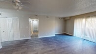 This single-floor residence offers a thoughtfully laid-out living space finished with a consistent, neutral color palette throughout. The expansive main living area is anchored by durable wood-look plank flooring and features a ceiling fan with light kit, textured ceilings, and a sliding glass door that invites natural light and provides outdoor access. A dedicated entry area flows seamlessly into the open-concept space, which connects to a pass-through kitchen counter with overhead cabinetry.

The galley-style kitchen is equipped with white cabinetry, speckled countertops, a stainless steel sink, a dishwasher, an electric range, and a stainless steel refrigerator, offering efficient use of space and ample storage.

The bedrooms are carpeted for comfort, each featuring ceiling fans, closets with sliding doors, and windows that allow for natural light. The hallway corridor connects the living areas to the private sleeping quarters with ease.

The bathrooms are cleanly finished, each featuring a tub and shower combination with tiled surrounds, chrome fixtures, and vanities with speckled countertops. Throughout the space, consistent trim work, neutral walls, and practical ventilation systems contribute to a clean, move-in-ready ambiance suitable for everyday living.