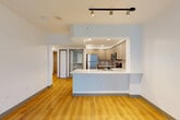 Located on the 10th floor at 1919 6th Ave in Seattle, WA, this efficiently laid-out unit offers a well-considered floor plan that maximizes its compact footprint. The open-concept living, dining, and kitchen area is anchored by warm hardwood-style flooring that flows throughout the space, creating a cohesive and inviting atmosphere. A wall of floor-to-ceiling windows in the living area fills the space with abundant natural light and frames sweeping views of Seattle's urban skyline.

The kitchen is a standout feature, showcasing a large peninsula with a striking white quartz countertop accented by subtle veining. Taupe shaker-style cabinetry lines the walls, complemented by a tile backsplash and a full suite of stainless steel appliances, including a refrigerator, range, microwave, and dishwasher. Track lighting above the peninsula adds a modern touch.

The bathroom offers a clean, contemporary design with a wide quartz vanity, ample drawer storage, a large mirror, and a tiled shower. Three closets — including a spacious walk-in outfitted with multi-level shelving and hanging rods — provide exceptional storage. The entrance hall connects all areas with ease, completing this polished and functional urban residence.
