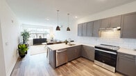 Located on Springside Lane in Middletown, CT, this well-appointed one-bedroom, one-bathroom unit offers a thoughtfully designed single-floor layout. The open-concept kitchen and living area forms the heart of the space, where gray shaker-style cabinetry, a white subway tile backsplash, and stainless steel appliances — including a range, dishwasher, and refrigerator — are complemented by a peninsula with pendant lighting overhead. Light wood-look flooring runs throughout the entire unit, creating a seamless, cohesive feel. The living area is bright and airy, benefiting from large windows that invite natural light and offer outdoor views of the surrounding neighborhood. A ductless mini-split system provides climate control in both the living area and the bedroom. The bedroom is a comfortable, well-lit retreat with sizable windows and ample room for a queen-sized bed and additional furniture. A double-door closet provides generous storage. The bathroom features a gray vanity with a white countertop, an LED-lit mirror, and subway tile detailing in the shower area. Clean white walls and warm flooring throughout give the entire unit a modern, move-in-ready aesthetic.