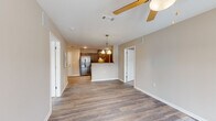 Located at 6306 Old Mooretown Rd in Williamsburg, Virginia, this two-bedroom, two-bathroom residence offers a practical and comfortable single-floor layout. The open-concept living and kitchen area forms the heart of the home, where durable hardwood-style flooring, neutral warm-toned walls, and ceiling fans create a bright and welcoming atmosphere. The kitchen is well-appointed with dark espresso cabinetry, granite-style countertops, stainless steel appliances including a French door refrigerator and electric range, and a peninsula with a double sink that opens to the living space — ideal for both cooking and entertaining. Natural light pours into the living room through a glass door, adding to the airy feel of the space. The primary bedroom is generously sized with plush carpeting, a ceiling fan, and windows that bring in ample daylight. The second bedroom mirrors this comfortable aesthetic. Each bathroom is clean and functional, with one featuring a modern floating vanity, sleek tile flooring, and contemporary lighting. Two dedicated closets provide practical storage solutions throughout. The overall design is cohesive and move-in ready, offering a comfortable lifestyle in a well-maintained Williamsburg community.