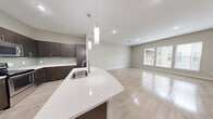 Located at 150 W Sam Houston Pkwy N in Houston, TX, this well-appointed one-bedroom, one-bathroom residence offers a thoughtfully designed layout with modern finishes throughout. The open-concept kitchen and living area serves as the heart of the home, featuring light wood-style flooring that extends across the space. The kitchen is outfitted with dark espresso cabinetry, white quartz countertops, a curved island with an undermount sink, stainless steel appliances including a dishwasher and refrigerator, and elegant pendant lighting overhead. A tile backsplash adds a refined touch. The living area flows seamlessly from the kitchen and is brightened by large windows that invite natural light and offer views of the surrounding community. The spacious primary bedroom is carpeted for comfort, includes a ceiling fan, and features generous windows that continue the theme of natural light. A walk-in closet with built-in shelving and hanging rods provides ample storage. The bathroom is well-equipped with a dual-sink vanity topped with granite countertops, a soaking tub with tiled surround, and large-format tile flooring. Clean neutral tones and recessed lighting throughout create a cohesive, contemporary ambiance.