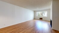 Located at 660 Veteran Ave in the desirable Westwood neighborhood of Los Angeles, this 2-bedroom, 2-bathroom residence offers a well-organized single-floor layout. Warm hardwood-style flooring flows throughout the main living areas and bedrooms, creating a cohesive and inviting atmosphere. The spacious living room is a standout feature, highlighted by a classic fireplace with glass doors and a large window that frames views of the surrounding greenery, filling the room with natural light. A textured ceiling is consistent throughout the unit. The kitchen is efficiently designed with ample light wood cabinetry, white countertops, tile flooring, a skylight-style overhead light, and black gas appliances including a range and dishwasher, along with a white refrigerator. The primary bedroom offers comfortable proportions, a sliding closet, and a window with outdoor views. The second bedroom is equally bright and open, with direct sightlines to the kitchen area. Both bathrooms are finished with tile flooring; one features a vanity with white cabinetry and a large mirror, while the other includes a tub-shower combo with elegant stone-look tile surround and mosaic accent detailing.