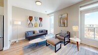Located on the 18th floor at 195 Dundas Street in downtown London, Ontario, this well-appointed one-bedroom, two-bathroom unit offers a thoughtfully designed layout across a single open floor. Light hardwood flooring flows throughout, complementing the warm neutral tones found in every room.

The modern kitchen is a standout feature, outfitted with crisp white cabinetry, a subway tile backsplash, stainless steel appliances, and a generous central island with quartz countertops — ideal for both cooking and casual dining. Pendant lighting adds a polished finishing touch. The kitchen opens seamlessly into the living room, which benefits from large floor-to-ceiling windows and access to a balcony, offering impressive elevated views of the London skyline.

The primary bedroom is a comfortable retreat, featuring hardwood flooring, a large window with panoramic city views, and access to a spacious walk-in closet with built-in wire shelving. The two bathrooms are finished with marble-style tile — one with a soaker tub and shower, the other with a sleek sliding glass shower enclosure and modern vanity.

A dedicated office provides a quiet, flexible space. The overall design is clean and contemporary, making efficient use of the available space throughout.