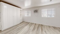 Located at 403 S Alvarado St in Los Angeles, CA, this efficiently designed one-bedroom, one-bathroom unit makes smart use of its single-floor layout. Light wood-style luxury vinyl flooring runs throughout the space, lending a clean, cohesive look that brightens every room.

The kitchen is a standout feature, showcasing crisp white shaker cabinetry, dark granite-style countertops, a stainless steel gas range, a black refrigerator, and an under-cabinet range hood — offering a well-appointed cooking space that maximizes functionality.

The open living and dining area flows naturally from the kitchen, creating a versatile space bathed in natural light from a window fitted with blinds. A wall-mounted air conditioning unit provides climate control throughout.

The spacious bedroom is notably generous, accommodating a large built-in white wardrobe system complete with shelving, drawers, and cabinet doors, as well as a mirrored sliding-door closet — providing abundant storage. Two windows allow natural light to fill the room.

The bathroom features tile-surround tub and shower combination with full-height wall tiles, a toilet, and wood-look tile flooring, maintaining a clean and functional aesthetic consistent with the rest of the unit.