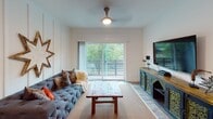Located at 250 District Dr in Asheville, NC, this single-floor residence offers a thoughtfully designed layout that balances contemporary finishes with eclectic, character-rich décor. A welcoming hallway introduces the space, featuring wood-look flooring and decorative wall art that sets an inviting tone throughout.

The kitchen is a standout feature, outfitted with sleek gray cabinetry, a white subway tile backsplash, stainless steel appliances, and a striking marble-look quartz island with pendant lighting overhead. Track lighting and additional pendant fixtures ensure the kitchen is well-lit and functional.

The living area is bright and open, anchored by a large sliding glass door that leads to a private balcony overlooking lush greenery, filling the room with natural light. Ceiling fans are present throughout, adding to the comfortable atmosphere.

Two bedrooms offer restful retreats, each featuring ceiling fans and distinct accent walls — one with shiplap paneling, another with a board-and-batten detail. One bedroom includes a walk-in closet. Two bathrooms are appointed with granite countertops and tiled shower surrounds. An in-unit laundry area with a full-size washer and dryer adds everyday convenience.