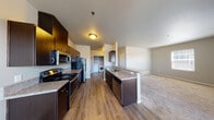 Located at 300 Boulder Falls Dr in Lebanon, Oregon, this single-floor residence offers a well-designed layout with modern finishes and functional living spaces throughout. The open-concept kitchen is a standout feature, equipped with dark espresso cabinetry, granite-style countertops, stainless steel appliances including a range, microwave, refrigerator, and dishwasher. A peninsula with bar seating connects the kitchen seamlessly to the living area, which is finished with durable hardwood-style flooring. The living room is generously sized with carpeted flooring and access to natural light through large windows. A dedicated in-unit laundry area with a full-size washer and dryer is conveniently situated just off the kitchen. The bedrooms are carpeted and bright, each featuring windows with blinds; at least one includes a closet with built-in shelving. The bathrooms are finished with tile flooring and granite-topped vanities — one features a full tub/shower combination with a window, while another serves as a three-quarter bath with a vanity, mirror, and grab bar. Neutral wall tones and consistent finishes create a cohesive, move-in-ready ambiance throughout the entire space.