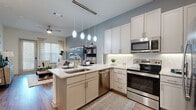 Located in McKinney, TX, this thoughtfully designed one-bedroom, one-bathroom residence offers a seamless open-concept floor plan that maximizes every square foot. The combined living, dining, and kitchen area serves as the heart of the home, featuring warm wood-look flooring, soft blue-gray accent walls, and a ceiling fan that enhances the airy atmosphere. A sliding glass door floods the living area with natural light and provides outdoor access.

The kitchen is a standout feature, boasting white shaker-style cabinetry, granite countertops, a herringbone tile backsplash, and a full suite of stainless steel appliances including a refrigerator, range, microwave, and dishwasher. A peninsula with pendant lighting provides bar seating, ideal for casual dining or entertaining. A pantry adds convenient storage.

The bedroom is a comfortable retreat, carpeted for warmth, with large windows, ample natural light, and access to two generously sized closets. The bathroom offers a granite-topped vanity with a framed mirror and a soaking tub-shower combo with tile surround. Additional highlights include a utility room, in-unit laundry, and a dedicated storage closet, making this a highly functional and well-appointed home.