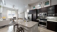 Located on Westheimer Road in Houston's desirable Galleria neighborhood, this well-appointed 2-bedroom, 2-bathroom residence offers a thoughtfully designed single-level layout. The open-concept kitchen and living area serves as the heart of the home, featuring a large granite-topped island with bar seating, dark espresso cabinetry extending to striking heights, stainless steel appliances including a gas range, and pendant lighting that draws the eye upward to the soaring ceilings. A ceiling fan adds comfort to the living area, which connects seamlessly to the dining space. The dining room is an intimate setting accented by a bold entry door and vibrant wall art. The primary bedroom is a serene retreat with soft carpet flooring, tall ceilings, and direct access to an en-suite bathroom finished with granite countertops, dark wood cabinetry, and a walk-in closet with built-in shelving. The second bedroom offers natural light through large windows with outdoor views. Both bathrooms mirror the same refined aesthetic with coordinating tile floors and granite vanities. A glass-paneled entry door fills the living area with natural light, completing this polished urban residence.