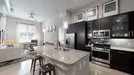 Located on Westheimer Road in Houston's desirable Galleria neighborhood, this well-appointed 2-bedroom, 2-bathroom residence offers a thoughtfully designed single-level layout. The open-concept kitchen and living area serves as the heart of the home, featuring a large granite-topped island with bar seating, dark espresso cabinetry extending to striking heights, stainless steel appliances including a gas range, and pendant lighting that draws the eye upward to the soaring ceilings. A ceiling fan adds comfort to the living area, which connects seamlessly to the dining space. The dining room is an intimate setting accented by a bold entry door and vibrant wall art. The primary bedroom is a serene retreat with soft carpet flooring, tall ceilings, and direct access to an en-suite bathroom finished with granite countertops, dark wood cabinetry, and a walk-in closet with built-in shelving. The second bedroom offers natural light through large windows with outdoor views. Both bathrooms mirror the same refined aesthetic with coordinating tile floors and granite vanities. A glass-paneled entry door fills the living area with natural light, completing this polished urban residence.