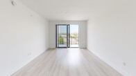Located at 101 W Camino Real in Boca Raton, FL, this modern one-bedroom, one-bathroom unit offers a well-designed, efficient layout across a single floor. Light wood-tone flooring flows consistently throughout the space, contributing to a clean and cohesive aesthetic.

The open-concept kitchen and living area serves as the heart of the unit. The kitchen features sleek, light-toned cabinetry extending to the ceiling, white quartz countertops, a stainless steel sink, and a full suite of stainless steel appliances including a refrigerator with ice and water dispenser, electric range, over-the-range microwave, and dishwasher. In-unit washer and dryer are also included. The living area is bright and airy, with a sliding glass door that opens to a private balcony offering outdoor views of the surrounding Boca Raton landscape.

The bedroom is a comfortable, well-proportioned room with a ceiling fan, a window with views to the outside, and access to a dedicated closet outfitted with wire shelving for organized storage.

The bathroom is finished with a white vanity, quartz countertop, large mirror, and a full tub-shower combination framed in large-format neutral tile. A hallway connects all areas of the unit cohesively. The overall ambiance is clean, modern, and move-in ready.