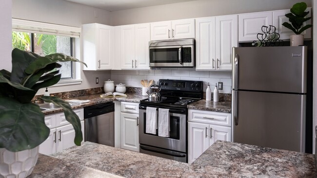Cook in style with a fully equipped kitchen featuring stainless steel appliances, granite-style countertops, and ample cabinetry. - Harper Grand Apartments