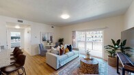 This single-floor unit offers a well-organized layout that includes a living area, dining space, kitchen, two bedrooms, two bathrooms, and a dedicated in-unit laundry area. The living room serves as the central gathering space, finished with warm hardwood-style flooring and a textured ceiling. Large sliding glass doors allow generous natural light to fill the room and provide direct access to a private balcony with outdoor views. A designated dining area sits adjacent, making the combined living and dining space both functional and inviting.

The kitchen is designed with light wood cabinetry, granite-style countertops, and black appliances including an electric range and built-in microwave. A double-door closet provides additional storage within the kitchen area.

Both bedrooms feature plush carpeting and windows with exterior views. The primary bedroom includes an en-suite bathroom with a wood-toned vanity and granite countertop. The second bathroom mirrors this design with a shower-tub combination and matching finishes. Hardwood-style flooring runs through both bathrooms. The in-unit laundry area accommodates a full-sized washer and dryer, adding everyday convenience to this thoughtfully arranged space.