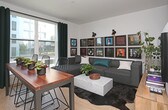 Located at 315 Airport Blvd in South San Francisco, this single-floor residence offers a thoughtfully designed interior with modern finishes throughout. The kitchen is outfitted with light wood cabinetry, white quartz countertops, a subway tile backsplash in soft blue-gray tones, and a full suite of stainless steel appliances including a range, over-the-range microwave, and dishwasher. Light hardwood flooring runs continuously through the space, lending warmth and cohesion.

The living area provides a comfortable, functional layout with ample wall space, as demonstrated by a striking gallery-style display wall suited for artwork or framed prints. The open floor plan connects the living and sleeping areas, maximizing the use of the available space.

A clean, well-lit hallway leads to an in-unit stacked washer and dryer tucked neatly behind a dedicated closet, offering practical convenience. Sliding doors throughout contribute to the contemporary aesthetic while optimizing floor space.

The bathroom features deep teal accent walls that create a bold, modern contrast against the warm wood vanity with integrated storage, a white undermount sink, and a tub-shower combination. The overall design is cohesive, urban, and efficiently executed.