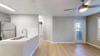Located at 4659 Dawson Blvd in Atlanta, Georgia, this single-floor residence offers a clean, modern aesthetic throughout. The open-concept layout connects the kitchen and living area seamlessly, with light wood-style flooring extending across the main living spaces and a neutral gray color palette that creates a bright, cohesive atmosphere.

The kitchen is well-appointed with stainless steel appliances, including a refrigerator, electric range, and microwave, complemented by gray cabinetry, white quartz-style countertops, a subway tile backsplash, and a peninsula with an integrated double sink — ideal for both cooking and casual dining.

The living area is generously proportioned, featuring a ceiling fan with light fixture, and a door leading to a private balcony that overlooks a tree-lined exterior with views of the surrounding community.

The bedroom offers ample space with its own ceiling fan, large windows that invite natural light, and access to a walk-in closet. The bathroom features full-height stone-look tile surrounding a soaking tub and shower combination, along with clean white fixtures for a polished finish.

Throughout the unit, textured ceilings, white baseboards, and consistent flooring tie each area together, offering a well-maintained and move-in ready living space in the Doraville area of metro Atlanta.