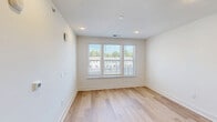 Located at 3818 Page Rd in Morrisville, NC, this single-floor residence offers a thoughtfully designed layout with clean, contemporary finishes throughout. Light-toned hardwood flooring flows seamlessly across all areas, creating a cohesive and airy feel.

The open-concept kitchen and living room serves as the heart of the unit. The kitchen is well-appointed with gray shaker-style cabinetry featuring matte black hardware, a white subway tile backsplash, a center island with a white countertop, stainless steel appliances including a refrigerator, range, microwave, and dishwasher, and a black matte single-basin sink. Recessed lighting illuminates the space effectively. A distinctive teal-painted interior door adds a pop of color and character to the area.

The bedroom is a comfortable, well-lit retreat featuring a ceiling fan with a built-in light, recessed lighting, and windows fitted with horizontal blinds that allow for natural light while maintaining privacy. The room offers views of the surrounding neighborhood.

A dedicated walk-in closet is outfitted with white wire shelving and hanging rods on multiple walls, providing ample and organized storage. The consistent use of white walls and trim throughout the unit contributes to a bright, clean, and modern ambiance.