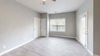 Located at 8800 Hollow Creek Cir in Charlotte, NC, this one-bedroom, one-bathroom residence offers a well-designed single-level layout with modern finishes throughout. Wood-look luxury vinyl plank flooring extends across all areas of the home, complementing the cool gray paint palette that creates a clean, contemporary aesthetic.

The open-concept living area is bright and welcoming, featuring a ceiling fan and a glazed entry door that allows natural light to filter in. A dedicated window with blinds frames a view of the surrounding greenery, enhancing the sense of openness. The space flows seamlessly into the kitchen, which is equipped with stainless steel appliances — including a refrigerator, range, and microwave — alongside gray shaker-style cabinetry and white quartz-style countertops. A single-basin sink and ample upper and lower cabinet storage make this kitchen both functional and stylish.

The bedroom is a well-proportioned private retreat featuring a ceiling fan, a built-in shelf ledge, and a window that brings in natural daylight. The full bathroom includes a tub-shower combination with white tile surround, a single-sink vanity with a white countertop, brushed nickel hardware and fixtures, and a large mirror above the vanity. Clean lines and neutral tones carry throughout, giving the entire residence a cohesive and move-in-ready feel.
