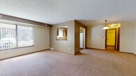 This single-floor residence located on Harbour Run S in Mentor-on-the-Lake, Ohio, offers a practical and well-organized layout with a consistent warm, neutral color palette throughout. The living area is generously proportioned, featuring wall-to-wall carpeting, a textured ceiling, and a large window fitted with vertical blinds that allows natural light to fill the space. A pendant light fixture is positioned near the dining area, adding a functional accent to the open layout.

The kitchen is connected to the living space via a pass-through window, creating an open, communicative flow between rooms. It features warm-toned wood cabinetry with ample upper and lower storage, gray laminate countertops, a double-basin sink, and hardwood-style flooring. White appliances, including a gas range and refrigerator, complete the kitchen setup. A window above the sink provides additional natural light.

The bedrooms are carpeted and feature natural light through windows with vertical blinds, along with sliding closet doors offering built-in storage. The bathroom includes a full tub-shower combination, a wood vanity with a wide mirror, gray countertops, and hardwood-style flooring, presenting a clean and functional design throughout.