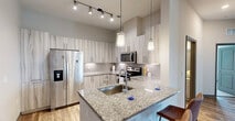 This well-appointed 3-bedroom, 2-bathroom residence in Sarasota, Florida offers a thoughtfully designed single-level layout with generous living space throughout. The open-concept living, dining, and kitchen area serves as the heart of the home, featuring warm wood-style flooring, crown molding accents, a ceiling fan, and a glass-paneled door leading to a private patio that brings in natural light. The modern kitchen is a standout, showcasing granite countertops, a peninsula with bar seating, pendant and track lighting, sleek two-tone cabinetry, a subway tile backsplash, and a full suite of stainless steel appliances. The three bedrooms offer plush carpeting, ample natural light from large windows, and ceiling fans for comfort. The primary bedroom features soaring ceilings and generous proportions. Four closets, including walk-in configurations, provide abundant storage. The bathrooms are finished with granite vanity tops, wood-look tile flooring, and clean white tile surrounds in the tub-shower combinations. Additional conveniences include an in-unit laundry area and a dedicated hallway connecting all living spaces efficiently. The overall aesthetic is clean, contemporary, and move-in ready.