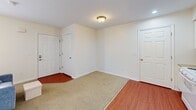 Located at 5596 Autumn Chase Dr in Columbus, OH, this efficient studio unit is thoughtfully designed to maximize functionality within a single-floor layout. The combined kitchen and living area forms the heart of the space, where white cabinetry and a full-size refrigerator are paired with a sink and stovetop along one wall, while the open living area accommodates comfortable seating with ease. Warm hardwood-style flooring runs through the kitchen and connecting areas, transitioning to plush carpet in the sleeping and lounge zones, creating a cozy, layered feel. A window brings in natural light and offers a view of the surrounding greenery, enhancing the bright, neutral-toned interior. Two closets provide ample storage, one of which features sliding doors and is conveniently positioned within the main living space. The full bathroom is clean and well-appointed, featuring a vanity with under-cabinet storage, a mirror, and a shower-tub combination. An in-unit laundry area adds everyday convenience. Throughout the space, crisp white walls and flush-mount lighting maintain a simple, tidy ambiance that is both practical and welcoming.