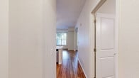 Located at 2551 38th Ave NE in St. Anthony, Minnesota, this single-floor unit offers a thoughtfully designed layout that makes efficient use of its space. Warm hardwood-style flooring runs continuously throughout, lending a cohesive and inviting feel to every room.

The open-concept kitchen and living area serves as the heart of the unit. The kitchen is outfitted with crisp white shaker cabinets, light quartz countertops, a stainless steel sink, and a full suite of stainless steel appliances including a refrigerator, electric range, dishwasher, and microwave. A peninsula with pendant lighting provides both additional counter space and a natural divide between the kitchen and living area. The living room benefits from multiple windows that invite natural light and offer views of the surrounding greenery, while a ceiling fan adds comfort overhead.

The bathroom is clean and functional, featuring a white vanity with a quartz countertop, a large mirror, and a tub-shower combination equipped with accessibility grab bars and a fold-down shower seat. The unit also includes two dedicated closets, each featuring wire shelving systems and hardwood-style flooring, offering practical and well-organized storage solutions. The overall aesthetic is bright, modern, and move-in ready.