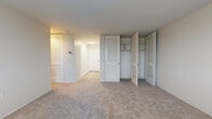Located at 910 Pennsylvania Ave in Kansas City, MO, this two-bedroom, one-bathroom residence offers a practical and well-organized layout across a single floor. The spacious primary bedroom is a standout feature, offering generous square footage, soft neutral carpeting, and large windows that frame views of the surrounding cityscape while allowing natural light to fill the room. A built-in radiator unit provides in-room climate control. The primary bedroom also benefits from an impressive array of louvered bifold closets, including a double closet with built-in shelving and hanging rods, offering excellent storage capacity. The second bedroom is similarly carpeted and bright, with a window that brings in natural light and a clean, open feel. The kitchen is efficiently designed with white cabinetry, light stone-look countertops, a full-size refrigerator, and wood-look vinyl flooring, providing a functional workspace. Adjacent to the kitchen, a glimpse into the living area reveals continued natural light from a large window. The bathroom features a full soaking tub with a clean, fully tiled white surround and a chrome grab bar. Throughout the residence, the neutral color palette and consistent finishes create a cohesive, move-in-ready environment.