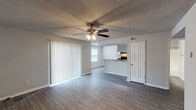 Located in Pensacola, FL, this single-story 2-bedroom, 2-bathroom residence offers a practical and comfortable layout designed for everyday living. The open living area features wood-style plank flooring, neutral gray walls, a textured ceiling, and a ceiling fan with light fixture. Large vertical blinds cover a sliding glass door, allowing natural light to fill the space. The living area flows seamlessly into the kitchen, which is configured as a galley-style layout. It includes white cabinetry, dark granite-style countertops, black appliances — including a range and refrigerator — and a double stainless steel sink. Light wood-style flooring and a window brighten the kitchen area. Both bedrooms are carpeted and feature ceiling fans and windows with blinds, providing a quiet and comfortable retreat. The two full bathrooms are each equipped with a single vanity featuring granite-style countertops, a tub/shower combination, and wood-style tile flooring. The neutral color palette and consistent finishes throughout the home create a cohesive and move-in-ready environment. Additional utility access is conveniently located within the unit.