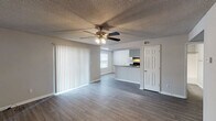 Located in Pensacola, FL, this single-story 2-bedroom, 2-bathroom residence offers a practical and comfortable layout designed for everyday living. The open living area features wood-style plank flooring, neutral gray walls, a textured ceiling, and a ceiling fan with light fixture. Large vertical blinds cover a sliding glass door, allowing natural light to fill the space. The living area flows seamlessly into the kitchen, which is configured as a galley-style layout. It includes white cabinetry, dark granite-style countertops, black appliances — including a range and refrigerator — and a double stainless steel sink. Light wood-style flooring and a window brighten the kitchen area. Both bedrooms are carpeted and feature ceiling fans and windows with blinds, providing a quiet and comfortable retreat. The two full bathrooms are each equipped with a single vanity featuring granite-style countertops, a tub/shower combination, and wood-style tile flooring. The neutral color palette and consistent finishes throughout the home create a cohesive and move-in-ready environment. Additional utility access is conveniently located within the unit.